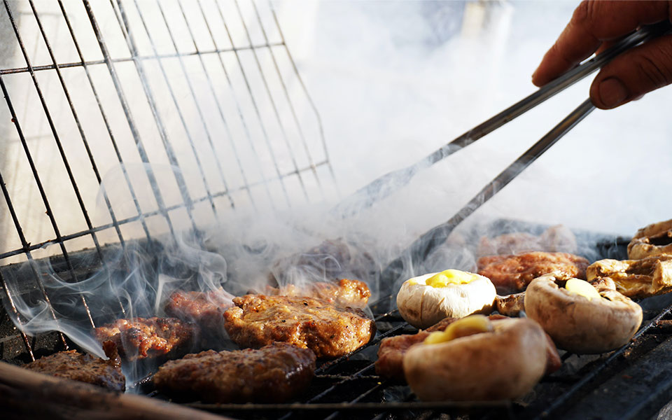 grillmaster-chef barbecued vlees en champignons op hete kolen
